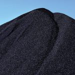 Tall pile of coal against blue sky