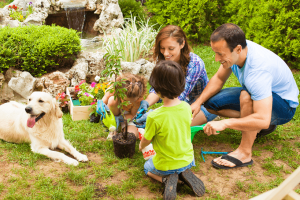 Mother and father with two kids and dog planting tree