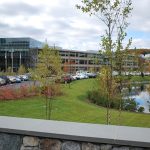 Company building with cars parked in lot near pond